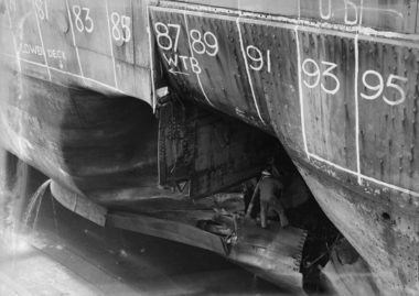 An unidentified officer inspects HMNZS Leander's extensive torpedo damage, Calliope Drydock 1943. Image: 2013.70.2650 An unidentified officer inspects HMNZS Leander's extensive torpedo damage, Calliope Drydock 1943.
