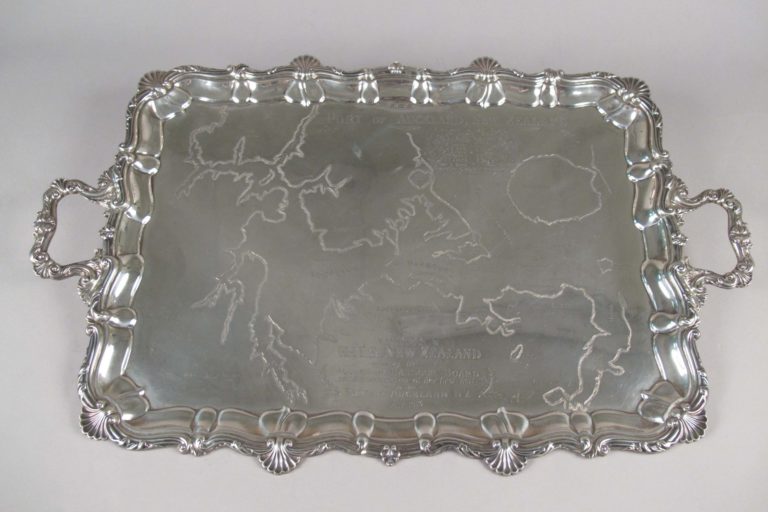 FT-0369-Silver-tea-service1 Silver tray with an engraved map of Auckland Harbour. Part of an eight piece silver tea service that includes kettle, salamander (stand), sugar bowl, cream jug, two engraved salvers and an engraved greenstone tablet. These were presented to HMS New Zealand by the Auckland Harbour Board. The inscription reads: ‘Presented to HMS NEW ZEALAND by the Auckland Harbour Board on the occasion of her visit to the Port of Auckland NZ May 1913’.