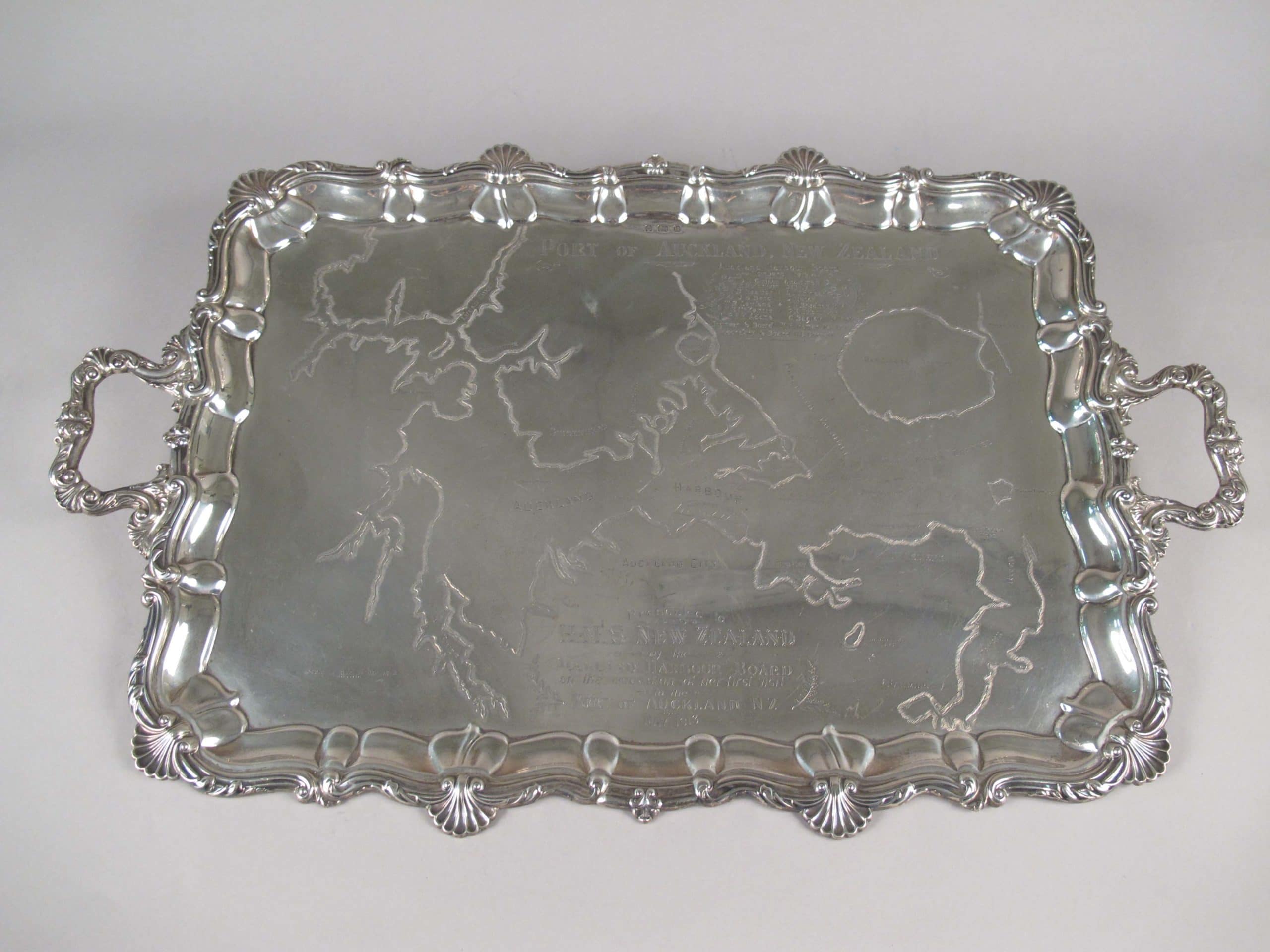 FT-0369-Silver-tea-service1 Silver tray with an engraved map of Auckland Harbour. Part of an eight piece silver tea service that includes kettle, salamander (stand), sugar bowl, cream jug, two engraved salvers and an engraved greenstone tablet. These were presented to HMS New Zealand by the Auckland Harbour Board. The inscription reads: ‘Presented to HMS NEW ZEALAND by the Auckland Harbour Board on the occasion of her visit to the Port of Auckland NZ May 1913’.
