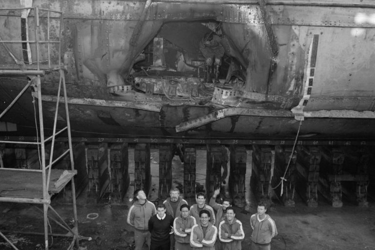 LT Hugh Aitken and Navy Dive Team standing in Calliope Dock in front of the hole in the Rainbow Warrior