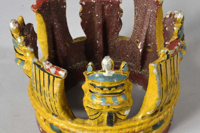 Metal painted crown attached to short section of wooden masthead. Masthead crown is believed to have been from HMS New Zealand.
